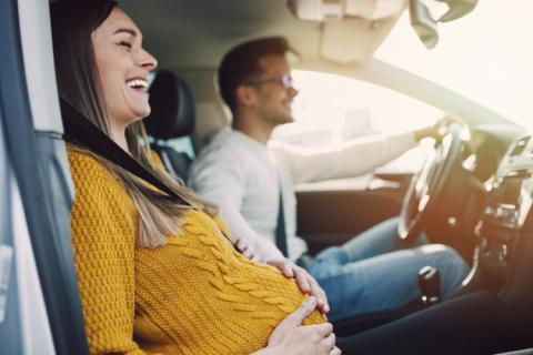 Mujer embarazada en un coche con su pareja.